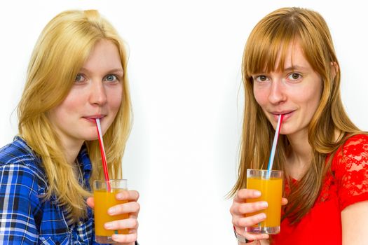 Two caucasian teenage girlfriends drinking orange juice isolated on white background