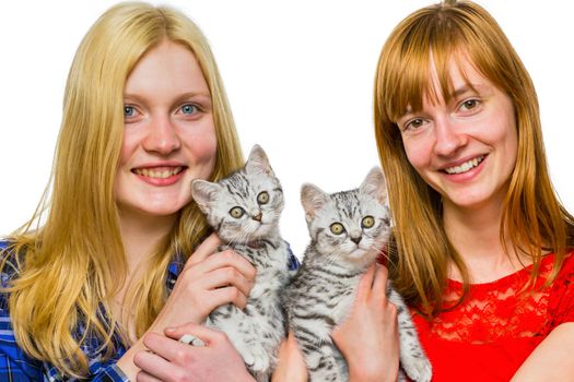 Two caucasian teenage girls showing young british shorthair black silver tabby cats isolated on white background