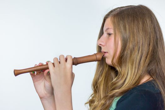 Blonde caucasian teenage girl with long blonde hair playing the flute isolated on white background