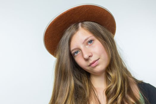 Blonde caucasian teenage girl with long blonde hair wearing brown hat isolated on white background