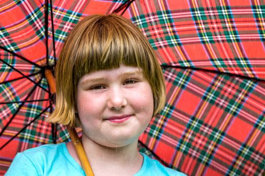 Young blonde dutch girl under red umbrella in rain