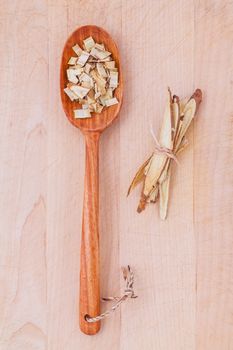 Licorice herbal medicine in wooden spoon, chopped and sliced on wooden table