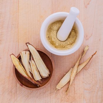 Licorice herbal medicine including powder, chopped and sliced root and mortar on wooden table