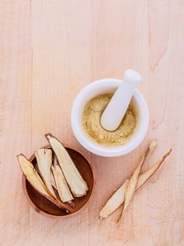 Licorice herbal medicine including powder, chopped and sliced root and mortar on wooden table