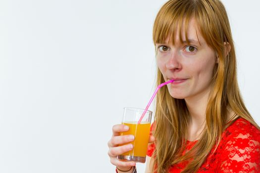 Redhead caucasian teenage girl drinking orange juice with straw isolated on white background