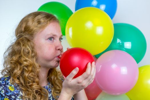 Dutch teenage girl blowing inflating colored balloons for birthday party