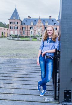 Blonde caucasian teenage  girl standing at entrance of castle