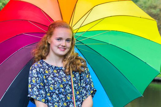 Caucasian teenage girl outdoors under umbrella with various colors