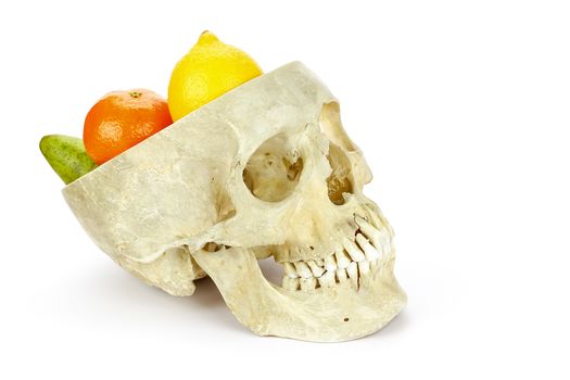 Human skull as fruit scale with fruit like lemon orange and pear isolated on white background