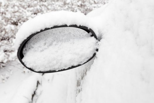 Car mirror filled with snow in winter season