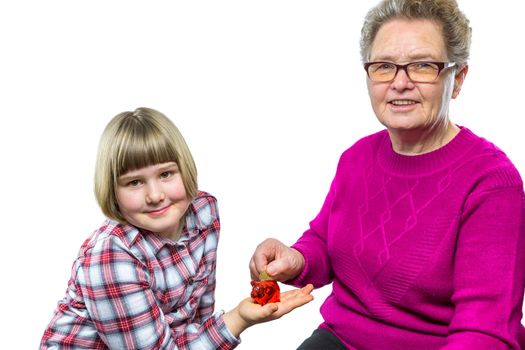 Caucasian grandmother putting euro coin in granddaughter's  piggy bank for saving isolated on white background