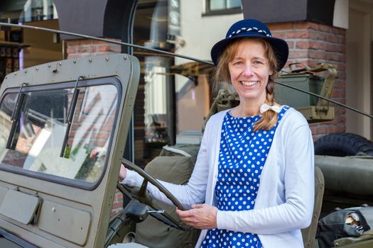 European middle aged woman steering military jeep to celebrate liberation day