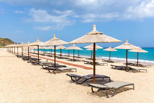 Many reed beach umbrellas in a row  for shade on empty beach and sea coast in Greece