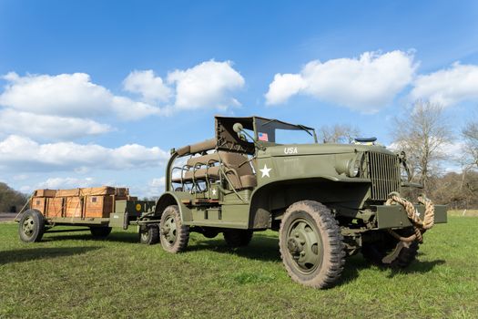 Military jeep pulling trailer carrying wooden boxes with bullets for war
