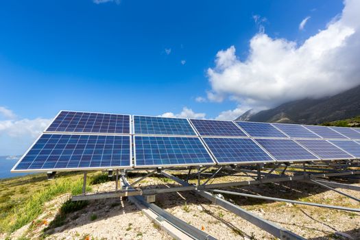 Row of blue solar panels on mountain in greece with blue sky