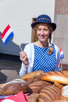 Caucasian woman with breads waving with dutch flag to celebrate liberation day in Holland