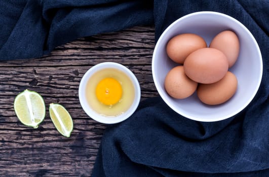 Fresh eggs in a  bowl on the old wooden table .