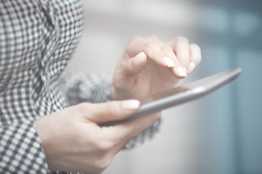 Woman at office behind the glass door working with digital tablet