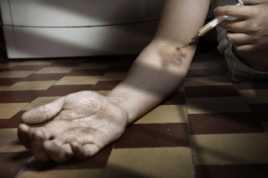 Hand of the narcotist with syringe on the floor. Artistic colors added