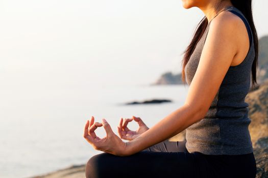 The woman meditating in a yoga pose on the tropical beach.