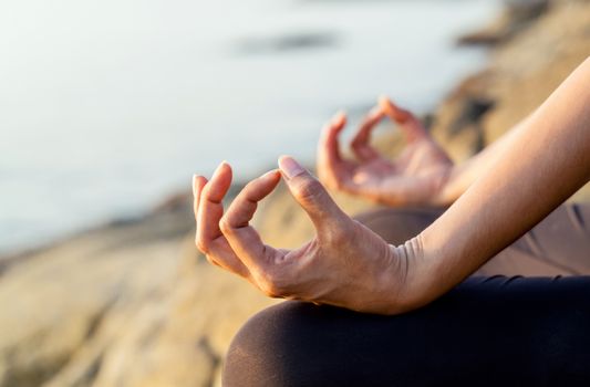 The woman meditating in a yoga pose on the tropical beach.