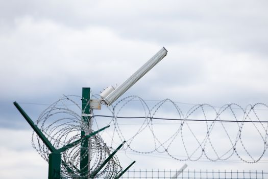 Wired fence with rolled barbed wires on white background