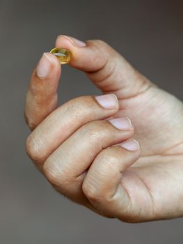 Pills of fish oil holding by young girl.