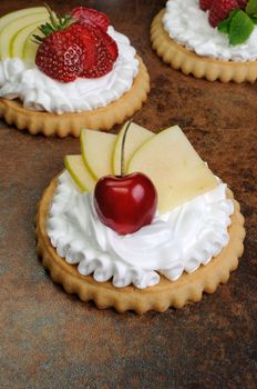 Tartlets with whipped cream on cherry and apple