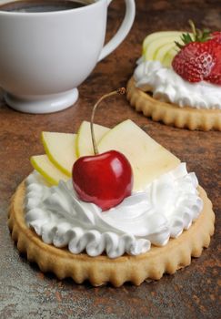 Tartlets with whipped cream cherries, apple and a cup of coffee