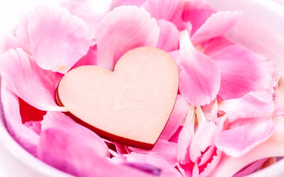 The wooden hearts on pink carnation petal.  - Concept for love and wedding .