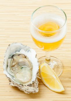 Fresh oysters with lemon and a glass of wine on a wooden table .