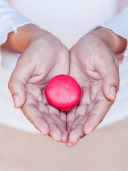 Female hands holding french macaroons. - Concept for giving sweet.