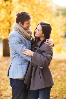 love, relationship, family and people concept - smiling couple hugging in autumn park