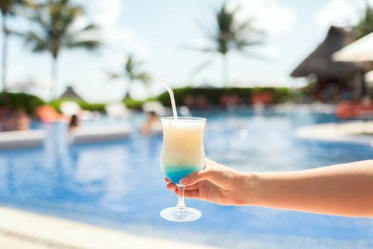 vacation, beverage and travel concept - close-up of female hand holding glass with cocktail