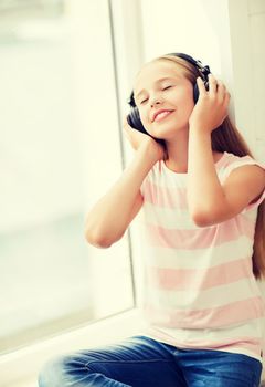 home, leisure, new technology and music concept - little girl with headphones at home