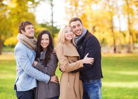 love, relationship, season, friendship and people concept - group of smiling men and women hugging in autumn park