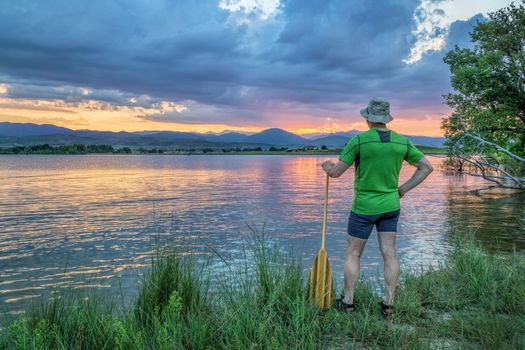 canoe paddler watching sunset over Rocky Mountains from a lake shore in Colorado near Loveland