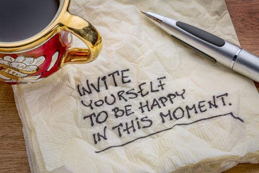 Invite yourself to be happy in this moment - inspirational advice on a napkin with a cup of coffee