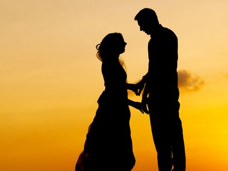 Silhouettes of bride and groom kissing at  sunset.