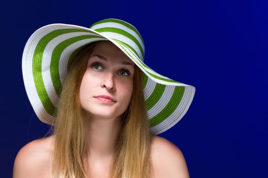 young pretty girl with a hat on her head. blue background. horizontal