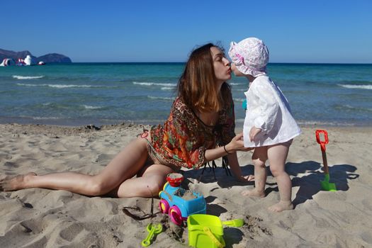 Mother kissing her daughter on the beach