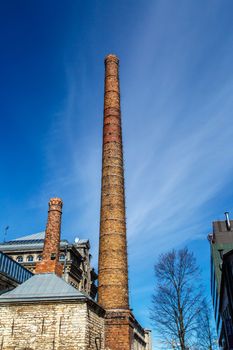 Close up bottom view of old historical orange brick chimney, on navy blue sky background.