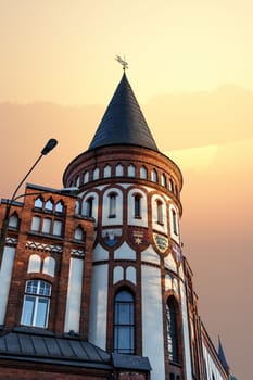 Close up bview of historical old house building with a small tower, on sunset or sunrise sky background.