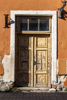 Close up view of yellow wooden door of the old orange building.
