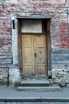 Close up view of yellow wooden door of the old red or brown wooden building.