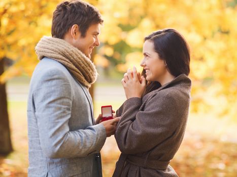 love, relationship, family and people concept - smiling couple with red gift box in autumn park