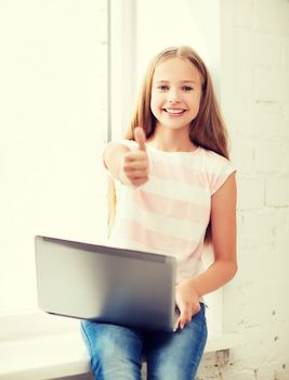 education, school, technology and internet concept - little student girl with laptop pc at school