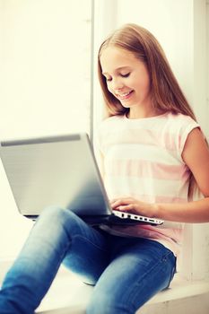 education, school, technology and internet concept - little student girl with laptop pc at school