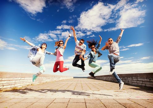 summer, sport, dancing and teenage lifestyle concept - group of teenagers jumping