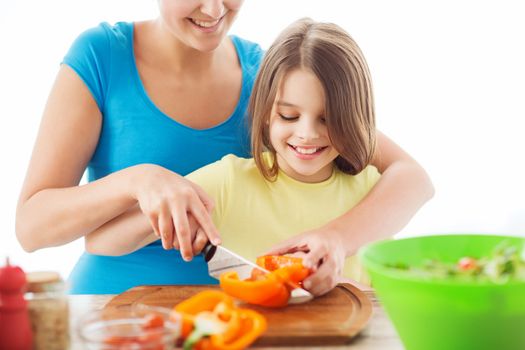 family, child, cooking and home concept - smiling little girl with mother chopping pepper in the kitchen